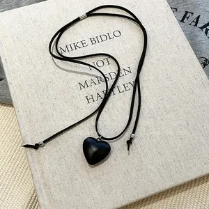 Close-up of a minimalist black resin heart pendant on an adjustable black cord necklace