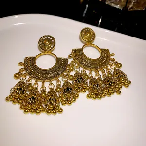 Macro view of vintage gold fan-shaped drop earrings with intricate bell tassels