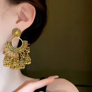 Detailed view of vintage golden fan earrings with ornate bell tassels for a retro look
