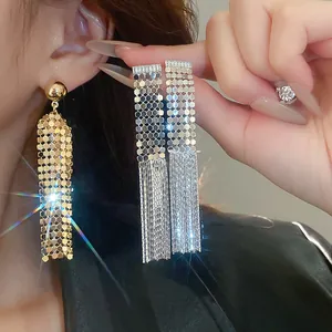 Dettaglio di eleganti orecchini geometrici con nappa in argento, finitura oro e argento.