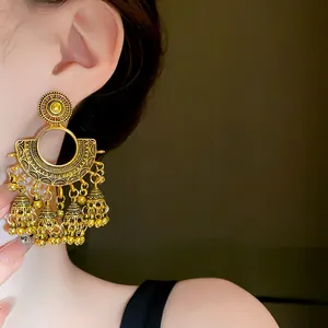 Close-up detail of vintage gold-colored fan-shaped bell tassel earrings on ear