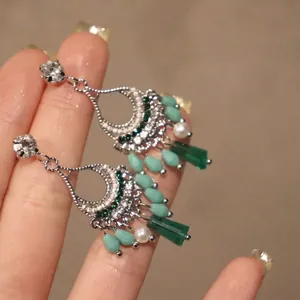Dettaglio macro di orecchini etnici in argento con perle di cristallo verde e perle.