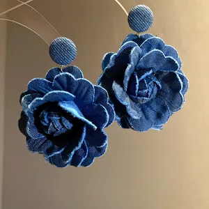 Dettaglio di eleganti orecchini a rosa in denim blu fatti a mano con petali testurizzati