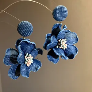 Vista dettagliata di orecchini a fiore in denim blu fatti a mano con centro di perline