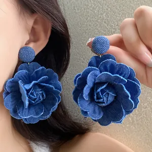 Primo piano dettagliato della trama di grandi orecchini a fiore in tessuto denim blu su orecchio.