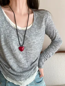 Close-up of minimalist red resin heart pendant necklace on an adjustable black cord.