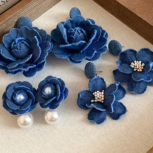 Dettaglio di orecchini a fiore in denim fatti a mano con perle e perline