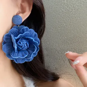 Primo piano di un orecchino a forma di rosa in denim blu indossato su un orecchio.
