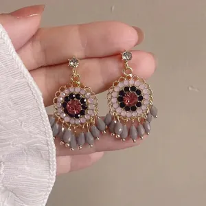 Dettaglio di orecchini vintage a nappa con cristalli, perline grigie e strass brillanti.