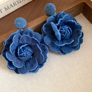 Primo piano macro della trama degli orecchini a fiore in tessuto denim blu scuro