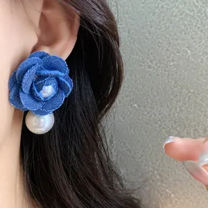 Primo piano di orecchini a fiore in denim con una lucente perla bianca pendente