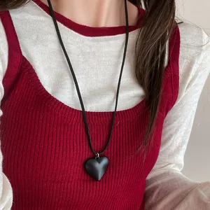 Close-up detail of a minimalist black resin heart pendant necklace worn on a model