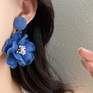 Dettaglio degli orecchini pendenti a fiore in denim blu con graziose perline