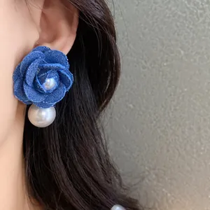 Primo piano di orecchino a fiore in tessuto blu con perla sul modello