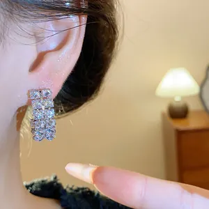Close-up of silver needle double-row cubic zirconia hoop earrings on ear