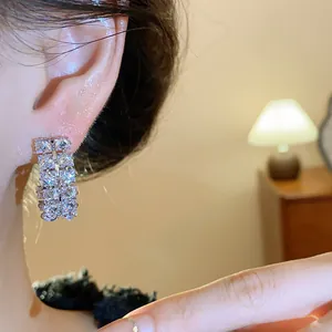 Macro view of elegant double-row zircon oval hoop earrings worn by a model in warm light