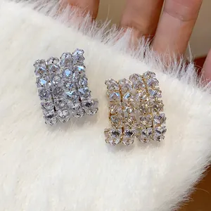 Detailed macro view of double-row cubic zirconia hoop earrings on soft white faux fur.