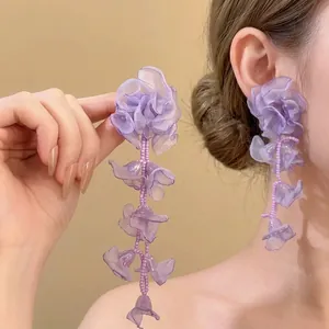 Detail der lila Stoffblumen Ohrringe mit Perlen Quasten für einen schicken Urlaubsstil