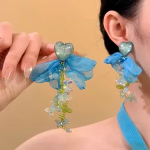 Nahaufnahme blauer Blumenohrringe mit Herzharz und Perlenquasten-Details