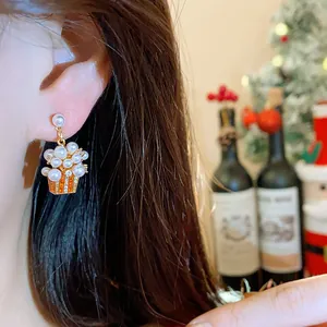 Close-up of 18K gold plated pearl earring with festive popcorn bucket design on ear.