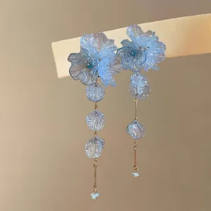 Close-up of elegant blue glass flower petal tassel earrings with long delicate chains.
