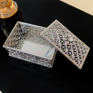 Detailed close-up of an ornate silver metallic jewelry box featuring a crystal hollow lid