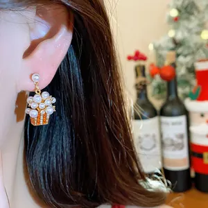 Close-up detail of a pearl and zircon stud earring on an ear with Christmas decor