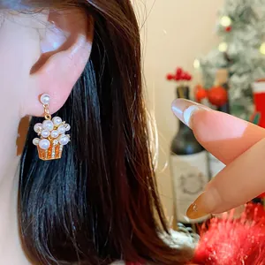 Detailed close-up of pearl gift box stud earring worn on ear with festive background