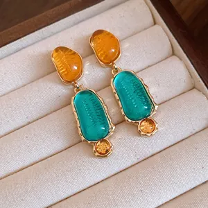 Primo piano di orecchini vintage in resina con forme ovali irregolari e montatura oro.