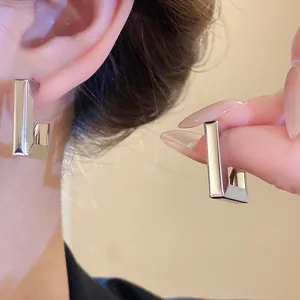 Detailed close-up of geometric silver-colored metal earrings with a minimalist design