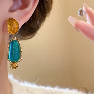 Dettaglio di orecchini vintage in resina irregolare verde e ambra sull'orecchio di una modella.