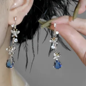 Close-up of elegant butterfly drop earrings featuring sparkling blue teardrop crystals.