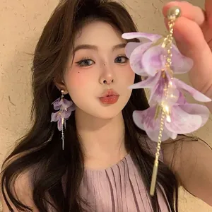 Close-up of elegant long purple petal tassel earrings with gold finish worn by a model