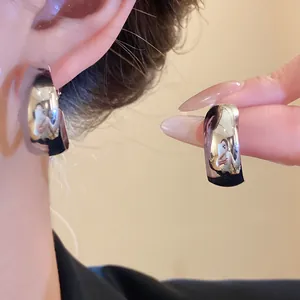 Close-up of high-polish gold hoop earrings showing reflective metallic texture and shine.