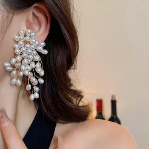 Detailed close-up showing oversized vintage floral pearl tassel earrings on an Asian model