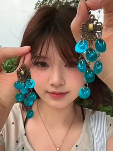 Asian model holding blue translucent flower tassel drop earrings in natural light