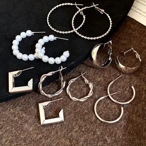 Close-up shot of a six-pair silver-tone earring set featuring pearls and hoops