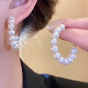 Elegant white pearl hoop earrings with a gold finish displayed on a model for detail