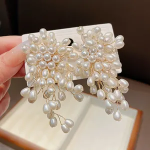 Close-up of elegant flower-shaped pearl tassel earrings with silver needles and luster.