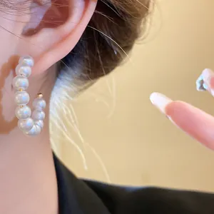 Detailed macro shot of elegant white pearl hoop earrings with gold accents worn by a model