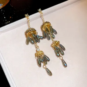 Detailed view of long gold tassel earrings with smoky grey teardrop beads and pearls