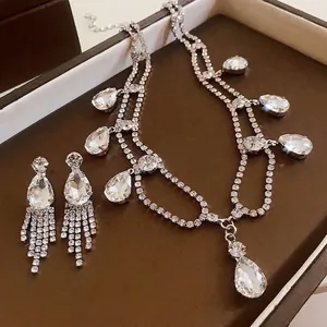Elegant teardrop crystal necklace and tassel earring jewelry set on a brown luxury box