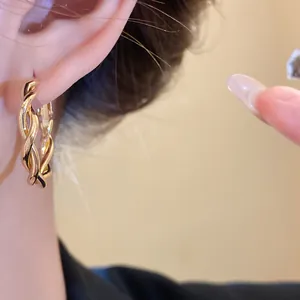 Close-up of elegant gold twisted hoop earring worn on ear, showing intricate vintage detail.