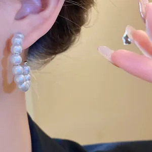 Macro detail of elegant white pearl hoop earrings showing refined texture and luster.