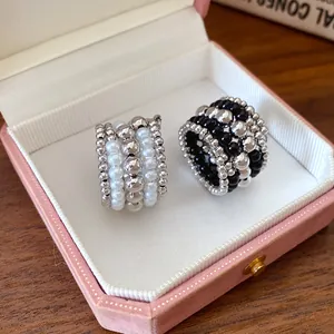 Detalle de anillos retro multicapa con perlas y esferas plateadas en un joyero rosa
