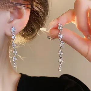 Close-up of elegant silver drop tassel earrings with sparkling rhinestones on an ear