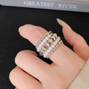 Vista detallada de un anillo multicapa vintage con perlas y cuentas metálicas plateadas