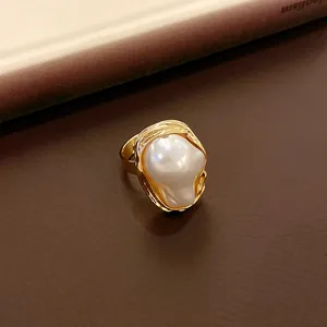 Close-up of a vintage-style ring with an irregular faux pearl in a gold setting.