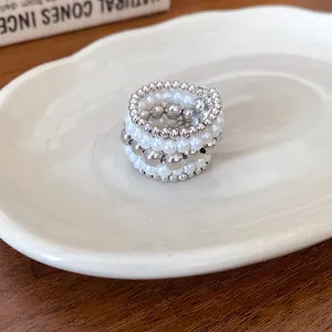 Vista detallada de un anillo multicapa retro con cuentas plateadas y perlas apiladas