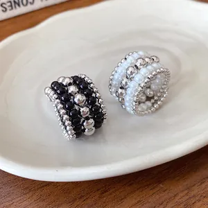 Vista macro detallada de anillos vintage multicapa con cuentas negras, perlas y plateadas